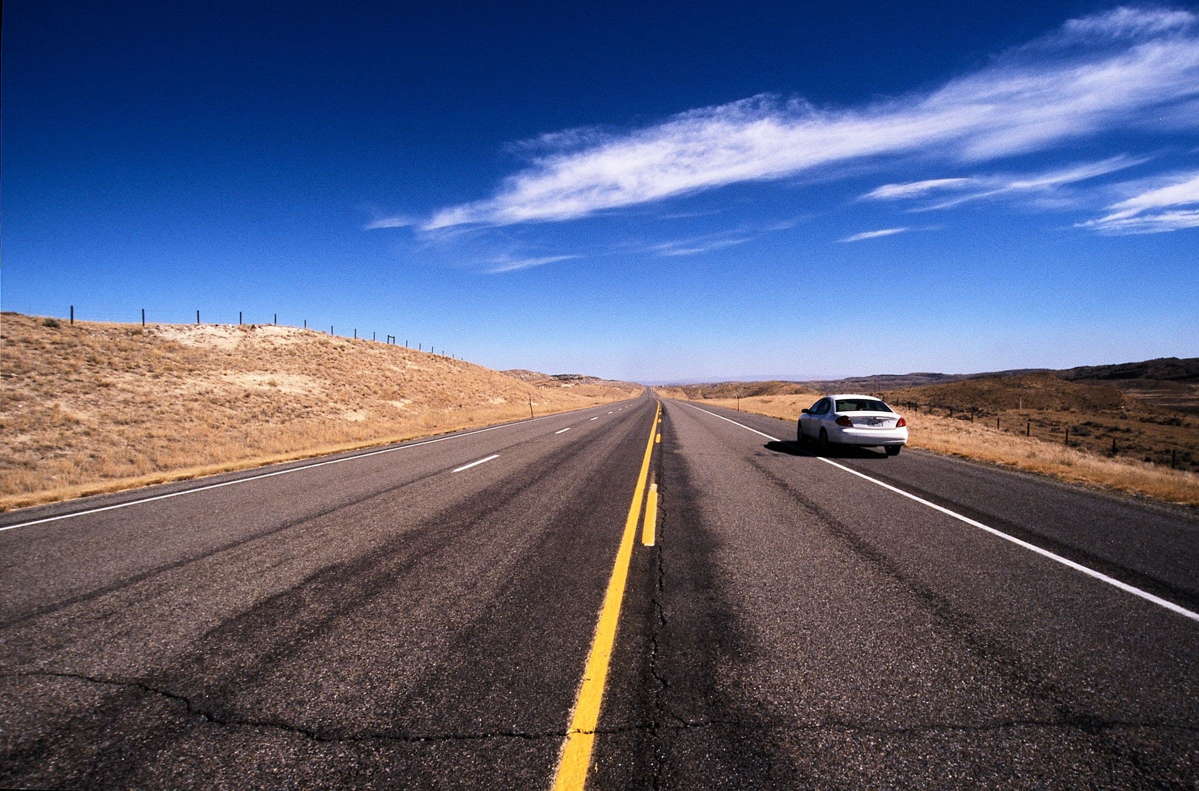 An open highway running through hills under a blue sky, near our windshield repair Black Hawk SD service area
