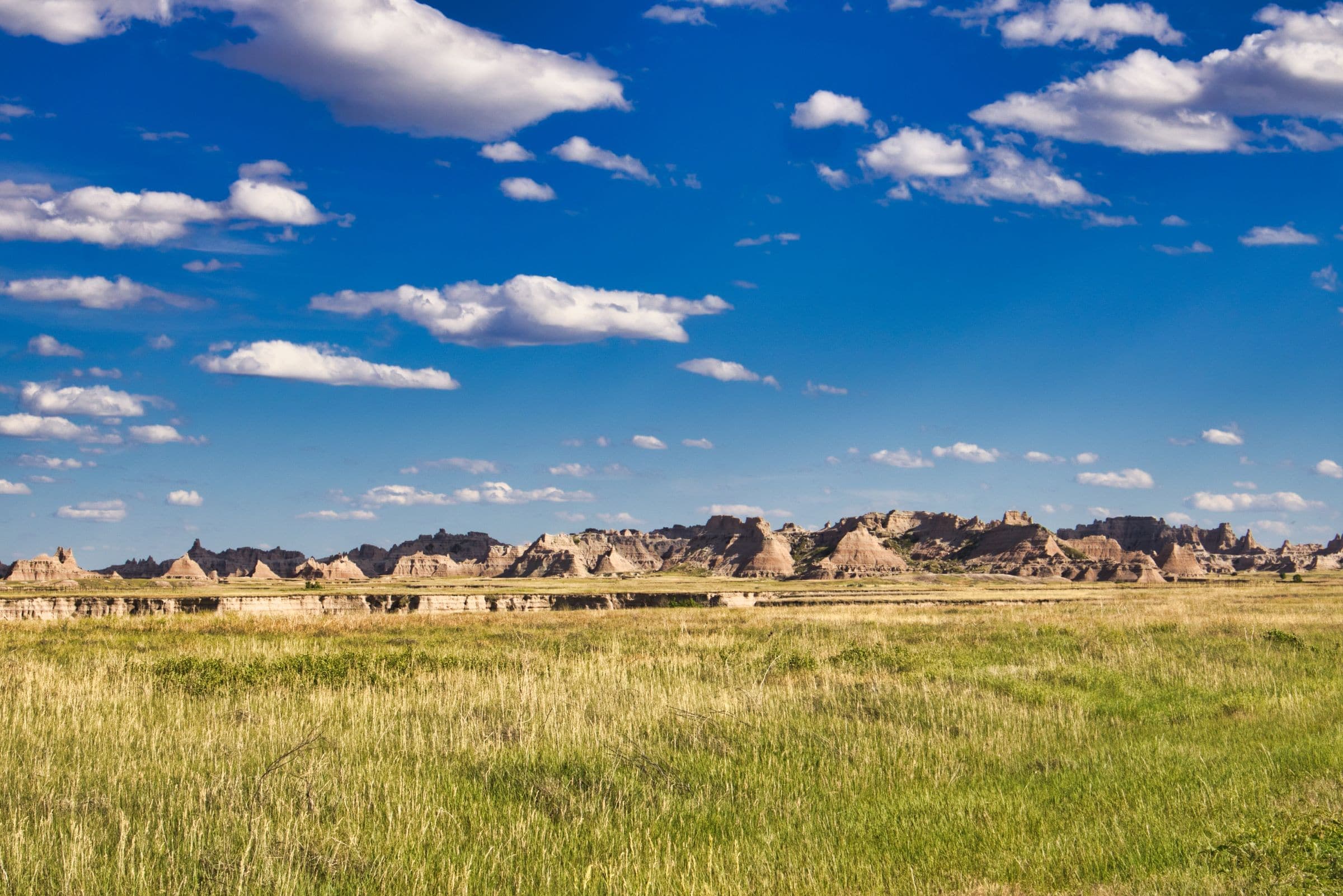 Badlands buttes rising beyond a grass prairie, near our windshield repair Wall SD service area